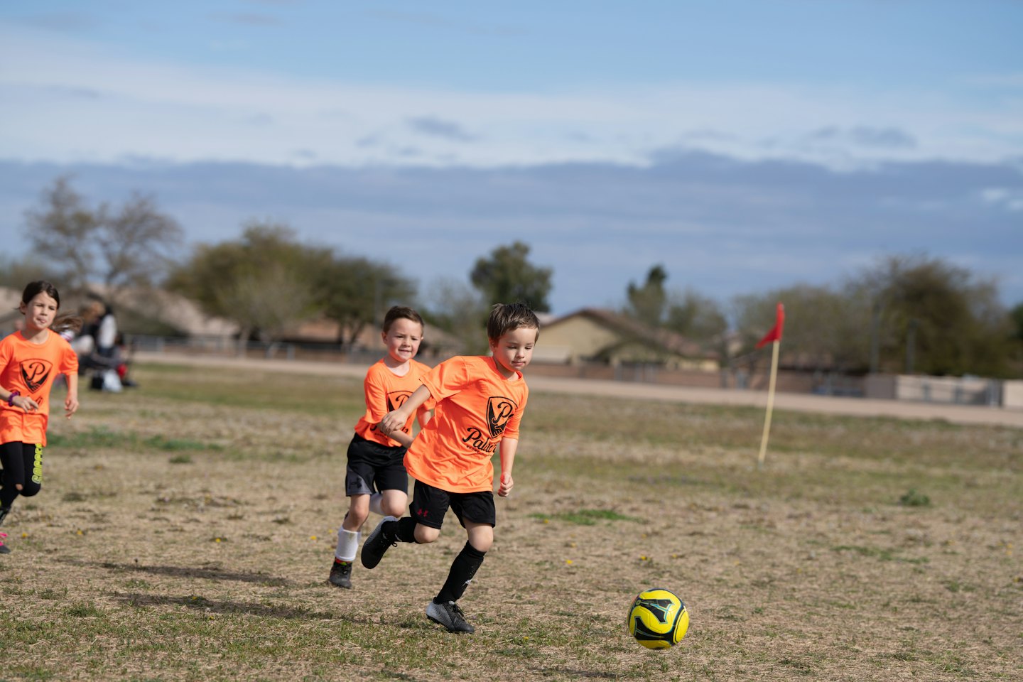Tre bambini in divisa da calcio giocano su un prato.